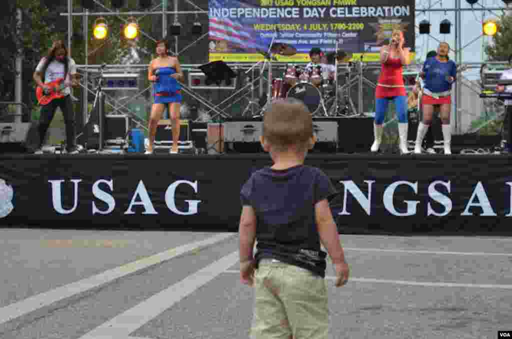 Ayden Massey, anak berumur 19 bulan dari Seoul, menyaksikan band "Absolute" dari Filipina yang ikut tampil dalam Perayaan 4 Juli di Barak Tentara Amerika di Garrison-Yongsan, Korea Selatan, 4 JUli 2012 (S.L. Herman/VOA).