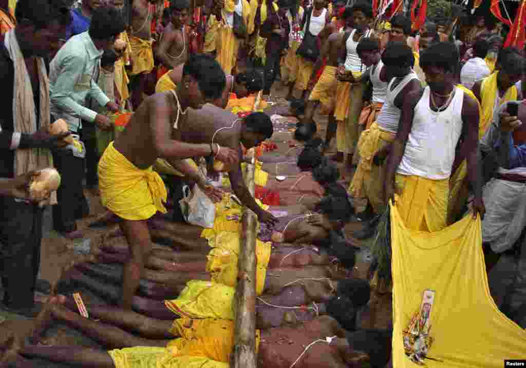 Para pria Hindu memecahkan kelapa yang diletakkan di atas punggung rekan-rekan mereka pada festival keagamaan "Danda" di kota Ganjam, negara bagian Odisha, India timur. 