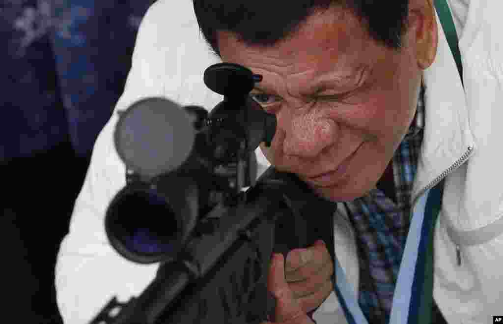 Philippine President Rodrigo Duterte checks the scope of a Chinese-made CS/LR4A sniper rifle during the presentation of thousands of rifles and ammunition by China at Clark Airbase in northern Philippines.
