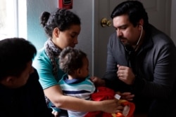 Dr. Martin Garza, right, a pediatrician who volunteers at Catholic Charities in McAllen, Texas, checks migrant families just released from immigration detention, March 15, 2019.