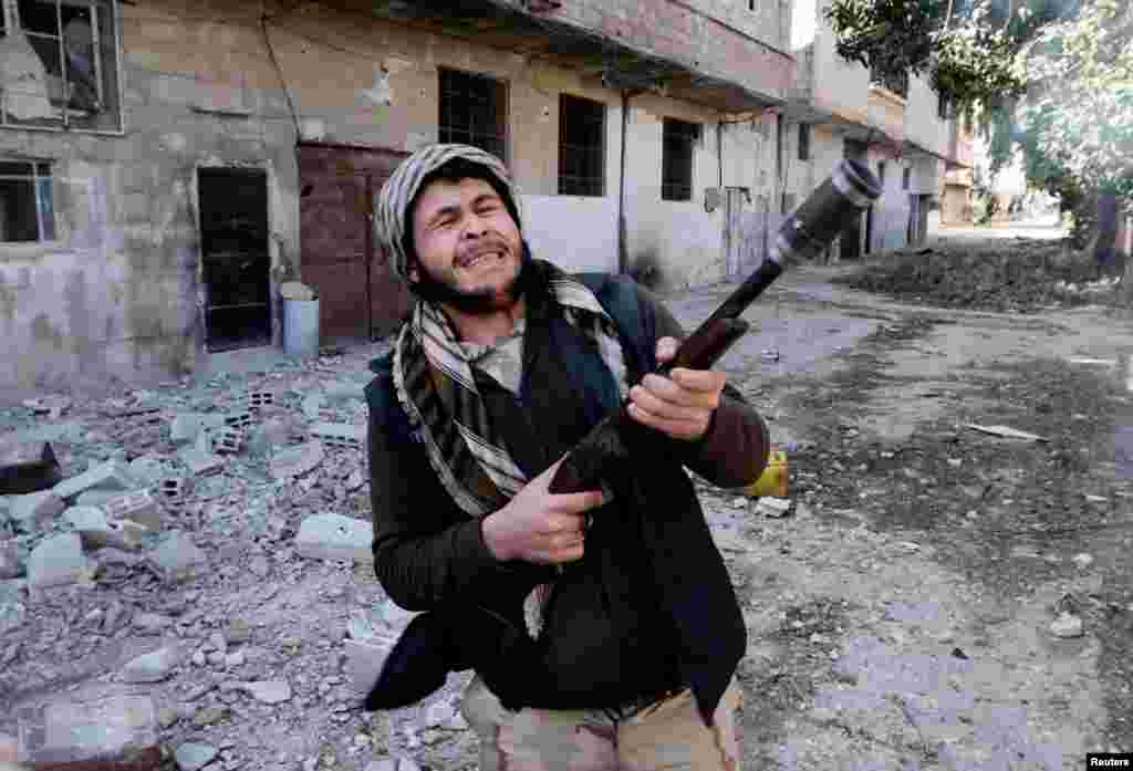 A fighter from the Free Syrian Army uses a shotgun to fire a grenade at Syrian Army soldiers in the Arabeen neigborhood of Damascus, February 9, 2013.