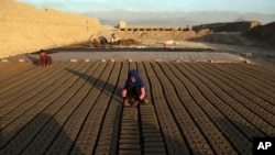In this June 19, 2019, photo, Afghan children help their father with work at a brick factory on the outskirts of of Kabul, Afghanistan.