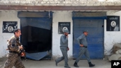 Afghan police walk past Islamic State militant flags on a wall, after an operation in the Kot district of Nangarhar province, Aug. 1, 2016.