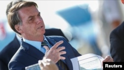 Brazil's President Jair Bolsonaro holds a paper with a print of the WhatsApp message with former minister Sergio Moro, written below in Portuguese: "This is gossip" as he leaves Alvorada Palace, in Brasilia, Brazil May 4, 2020.
