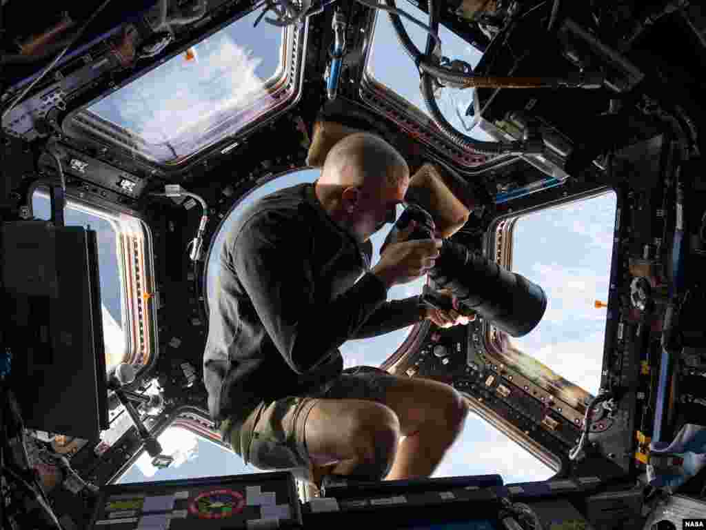 Inside the Cupola, NASA astronaut Chris Cassidy, an Expedition 36 flight engineer, uses a 400mm lens on a digital still camera to photograph a target of opportunity on Earth some 250 miles below the International Space Station.