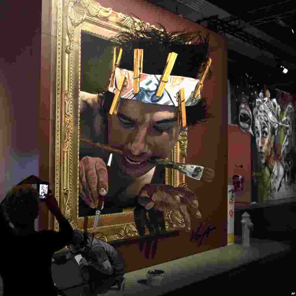 Seorang perempuan memotret lukisan karya seniman Meksiko Juandres Vera dalam pameran 'Art of the Street' di Magic City, Munich, Jerman.