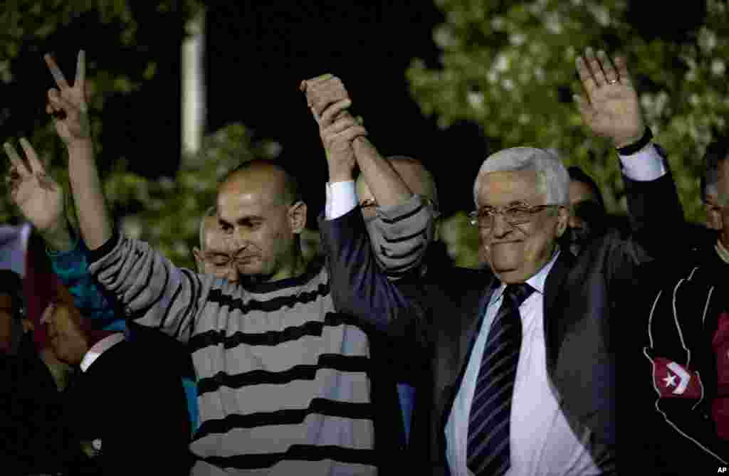 Palestina Presiden Mahmoud Abbas menggandeng tangan seorang tahanan yang dibebaskan selama upacara penyambutan di kantor pusat Otoritas Palestina, di Ramallah, Tepi Barat (30/10). (AP/Nasser Nasser)