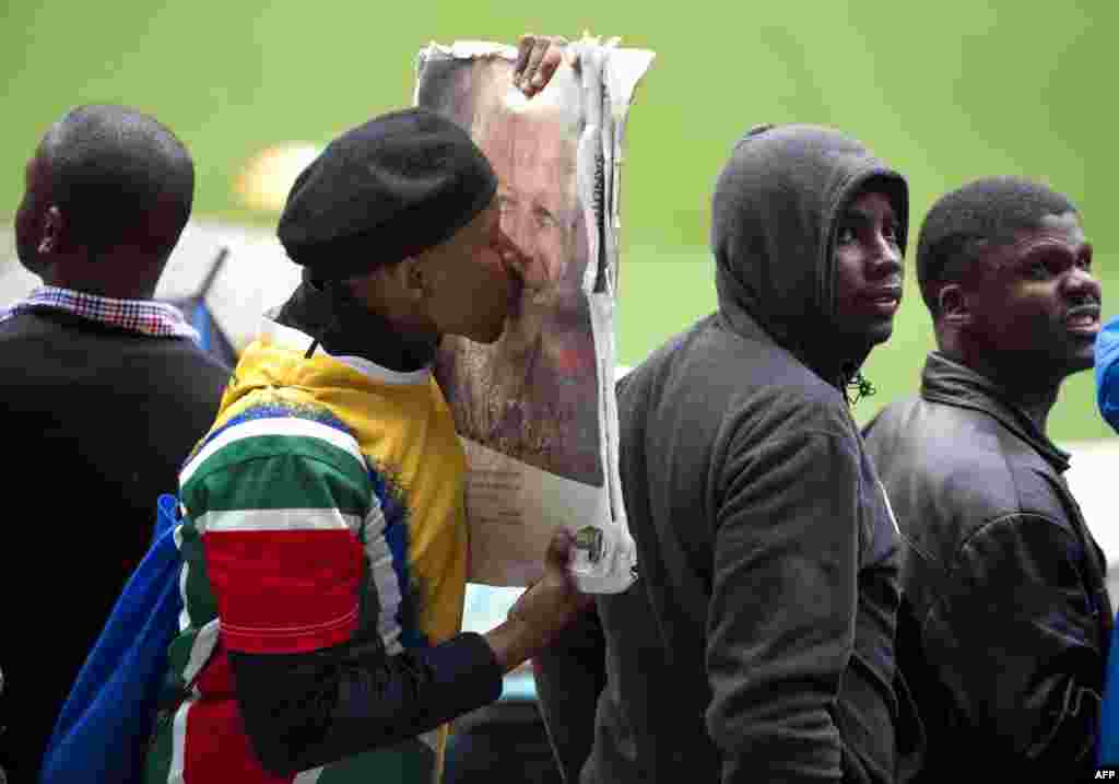 A man kisses the portrait of former South African President Nelson Mandela during his memorial service at the FNB Stadium (Soccer City) in Johannesburg.