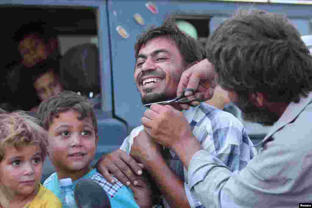 A man cuts the beard of a civilian who was evacuated with others by the Syria Democratic Forces (SDF) fighters from an Islamic State-controlled neighborhood of Manbij, in Aleppo Governorate, Syria, Aug. 12, 2016.