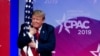 FILE - President Donald Trump hugs the American flag as he arrives to speak at Conservative Political Action Conference, CPAC 2019, in Oxon Hill, Md., March 2, 2019. 