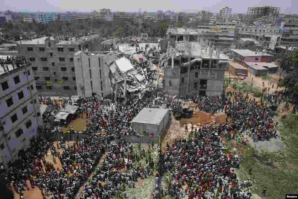 Massa berkumpul di antara reruntuhan bangunan, saat regu penyelamat tengah berupaya mencari para pekerja garmen yang diperkirakan masih terperangkap di bawah reruntuhan gedung Rana Plaza di Savar, 30 kilometer di luar Dhaka, Bangladesh 24 April 2013.