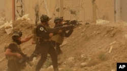 FILE - Security forces defend their headquarters against attacks by Islamic State extremists during sand storm in the eastern part of Ramadi, the capital of Anbar province, Iraq, May 14, 2015.