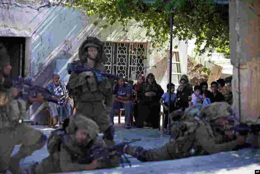 Seorang keluarga Palestina menatap tentara Israel dalam operasi militer untuk mencari tiga remaja yang hilang, dekat Tepi Barat kota Hebron, 15 Juni 2014.