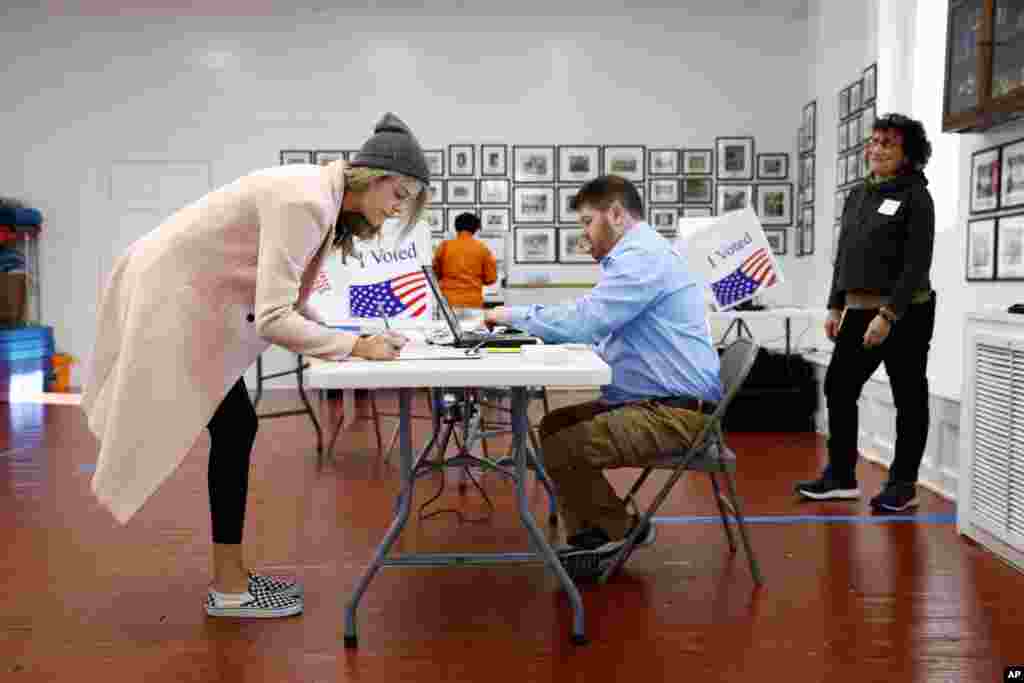 Marie McMahon, left, signs in to vote at a primary polling place, Feb. 29, 2020, in Charleston, S.C.