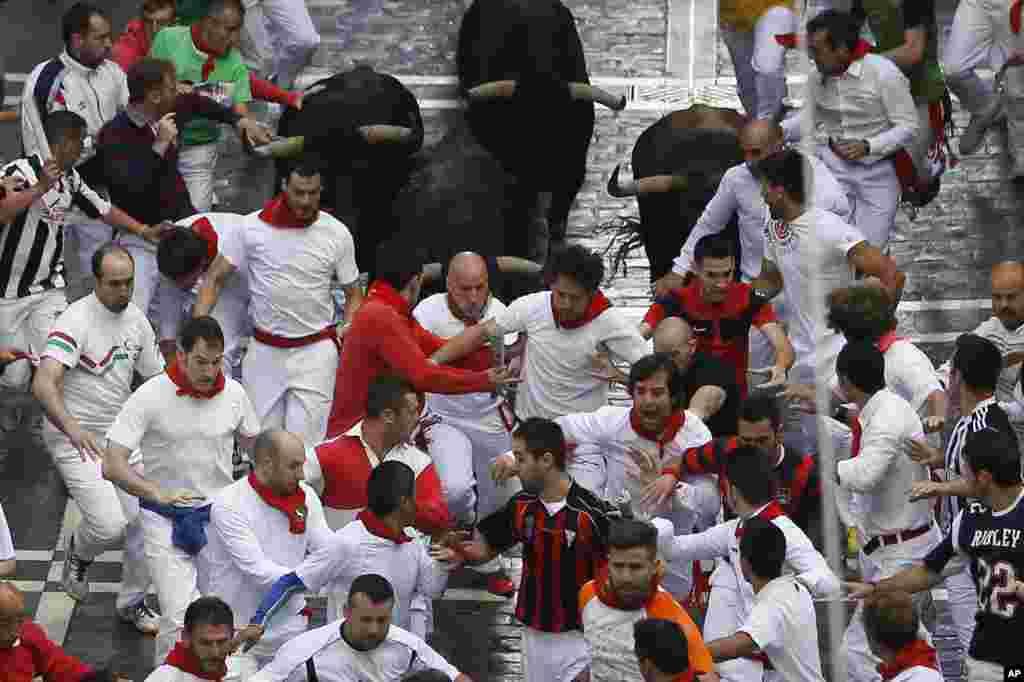 Banteng-banteng Jandilla berlari di tengah kerumunan orang dalam acara "Jangan Sampai Diseruduk Banteng" pada Festival San Fermin di Pamplona, Spanyol. Peserta dari seluruh dunia datang ke Pamplona setiap tahunnya untuk ambil bagian dalam delapan hari festival itu. 