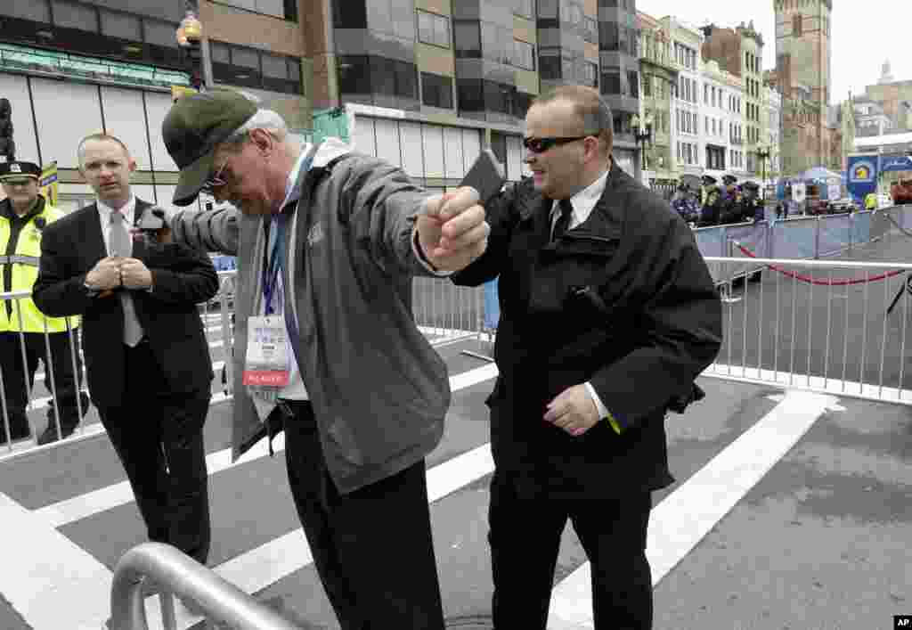 Petugas penegak hukum memeriksa seorang pria dekat garis finish Maraton Boston sebagai antisipasi kedatangan Wakil Presiden Joe Biden (15/4). (AP/Steven Senne)