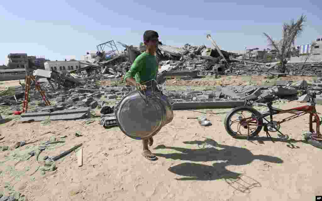 Seorang warga Palestina menyelamatkan apa yang ia bisa dari rumahnya setelah terkena serangan rudal Israel di Rafah, bagian selatan Jalur Gaza (9/7). (AP/Hatem Moussa)