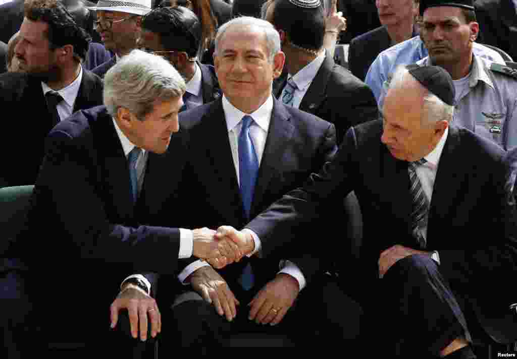 Israeli President Shimon Peres shakes hands with U.S. Secretary of State John Kerry as Prime Minister Benjamin Netanyahu sits between them during a ceremony marking Israel's annual day of Holocaust remembrance, at Yad Vashem, Jerusalem, April 8, 2013.