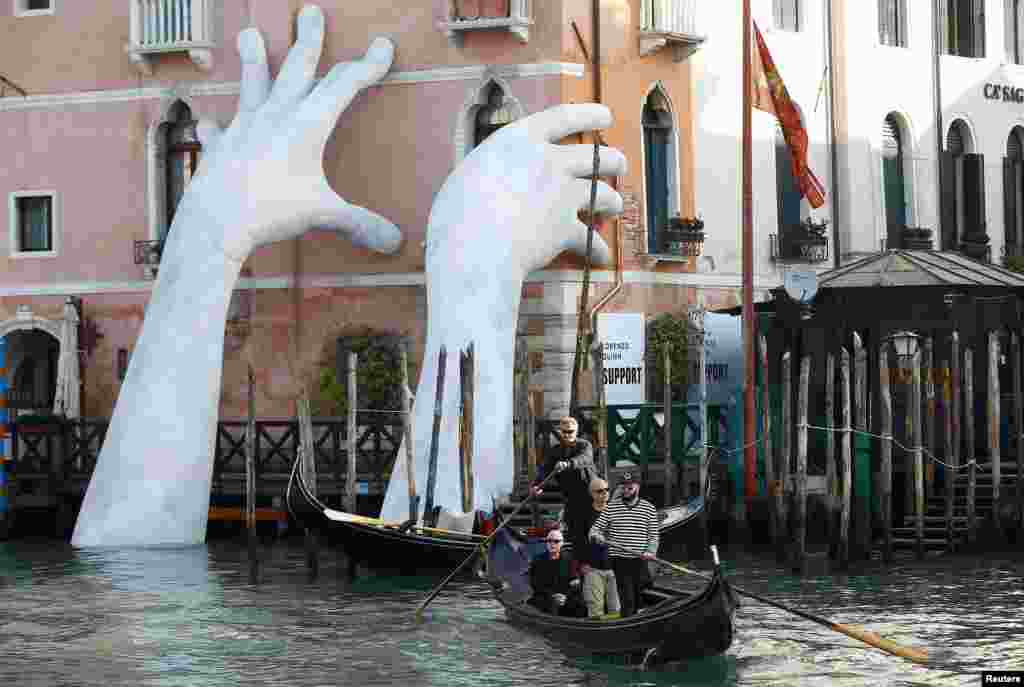 Italian artist Lorenzo Quinn's installation called " Support" is seen on Ca' Sagredo palace during the 57th La Biennale of Venice, in Venice, Italy.