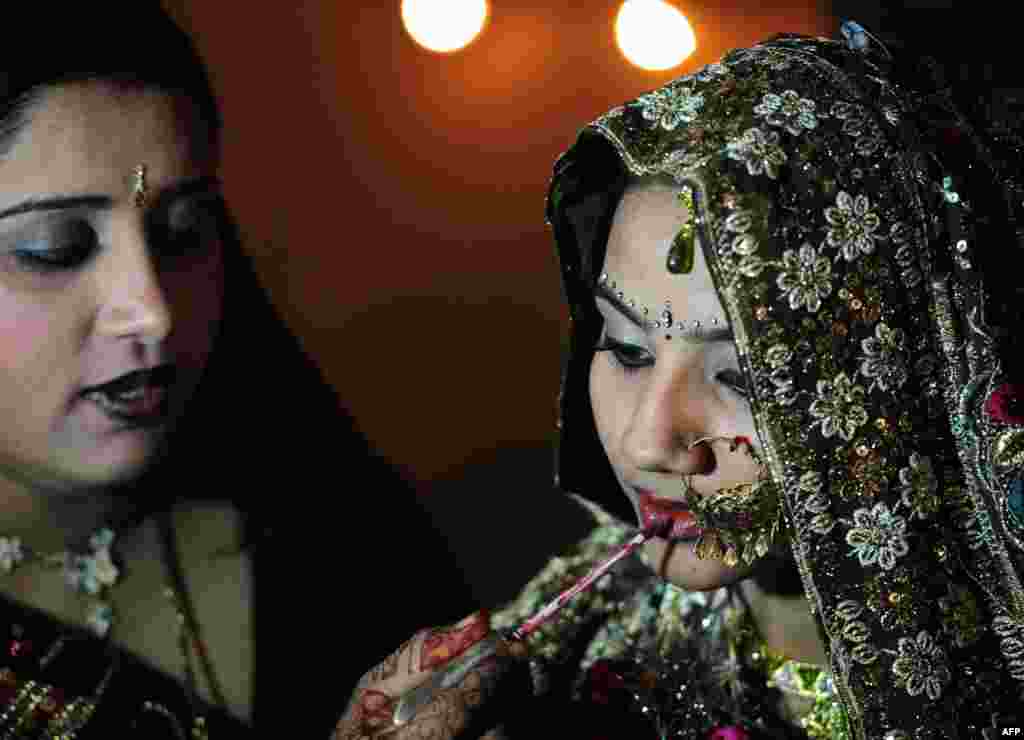 Seorang pengantin perempuan Pakistan Hindu mendapat sentuhan terakhir pada hiasan wajahnya dari seorang kerabat pada acara pernikahan masal di Karachi. Sekitar 50 pasangan pengantin Hindu berpartisipasi dalam upacara perkawinan masal yang diselenggarakan oleh Dewan Hindu Pakistan. 