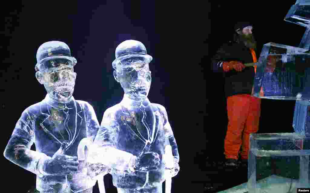 Sculptor Juuso Partanen of Finland carves a sculpture near other sculptures based on characters of comic strips at the Brussels Ice Magic Festival, Belgium.