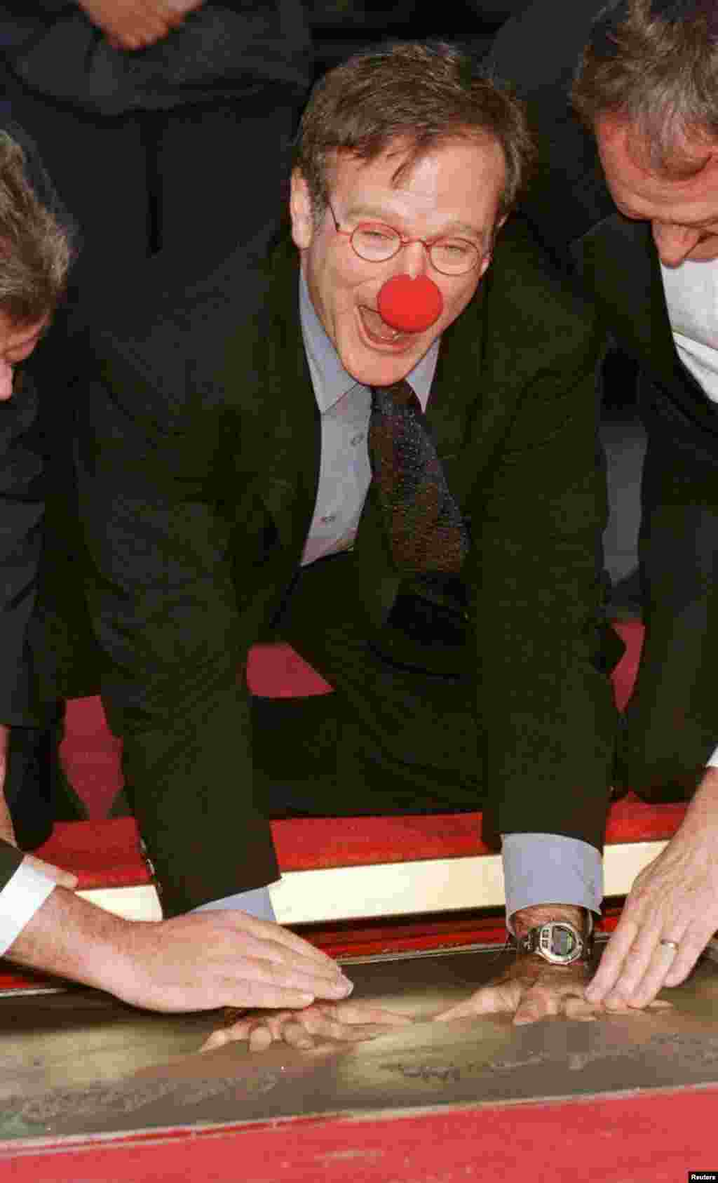 Academy Award-winning actor Robin Williams, wearing a prop from his new film "Patch Adams" places his handprints in cement during ceremonies to honor him at Mann's Chinese Theater, in Hollywood, Dec. 22, 1998.