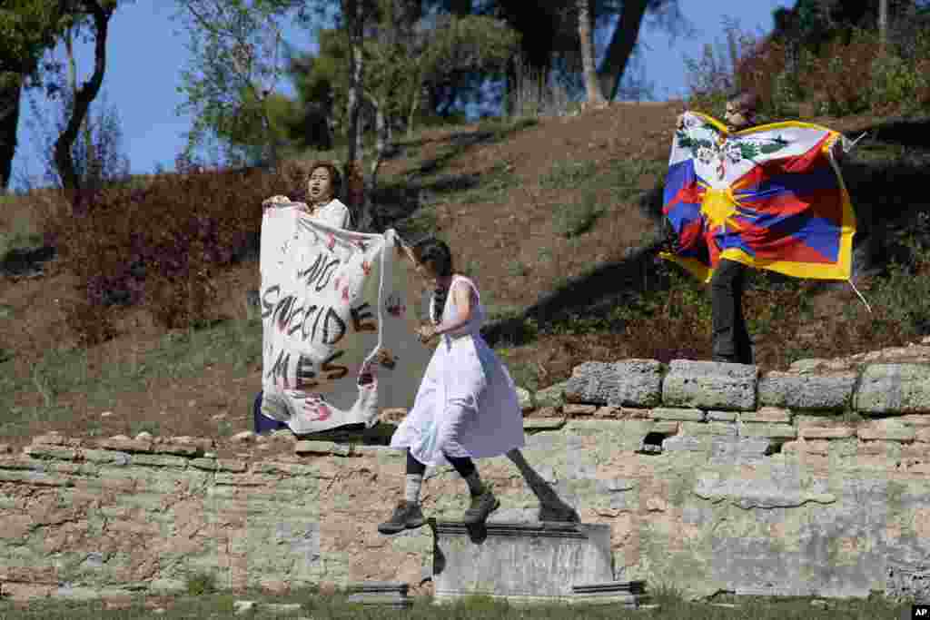 Protesters displaying a Tibetan flag and a banner reading "No genocide games" enter the grounds during the lighting of the Olympic flame at Ancient Olympia site, birthplace of the ancient Olympics in southwestern Greece.