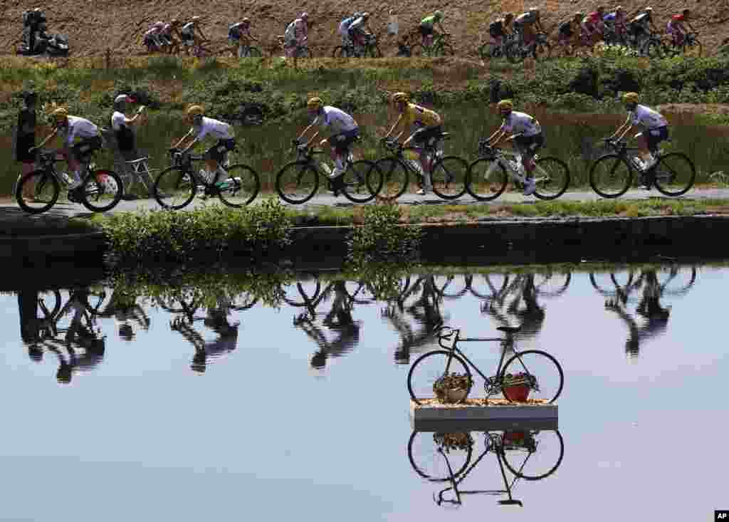 Britain's Geraint Thomas, wearing the overall leader's yellow jersey, and new overall leader Britain's Chris Froome, left of Thomas, are reflected in a pond as they ride in the pack during the fifth stage of the Tour de France cycling race over 160.5 kilometers (99.7 miles) with start in Vittel and finish in La Planche des Belles Filles, France.