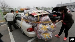A South Korean worker, left, who arrives with electronic products from North Korea's Kaesong is helped by a South Korean woman who greeted him at customs in Paju, South Korea, April 8, 2013.