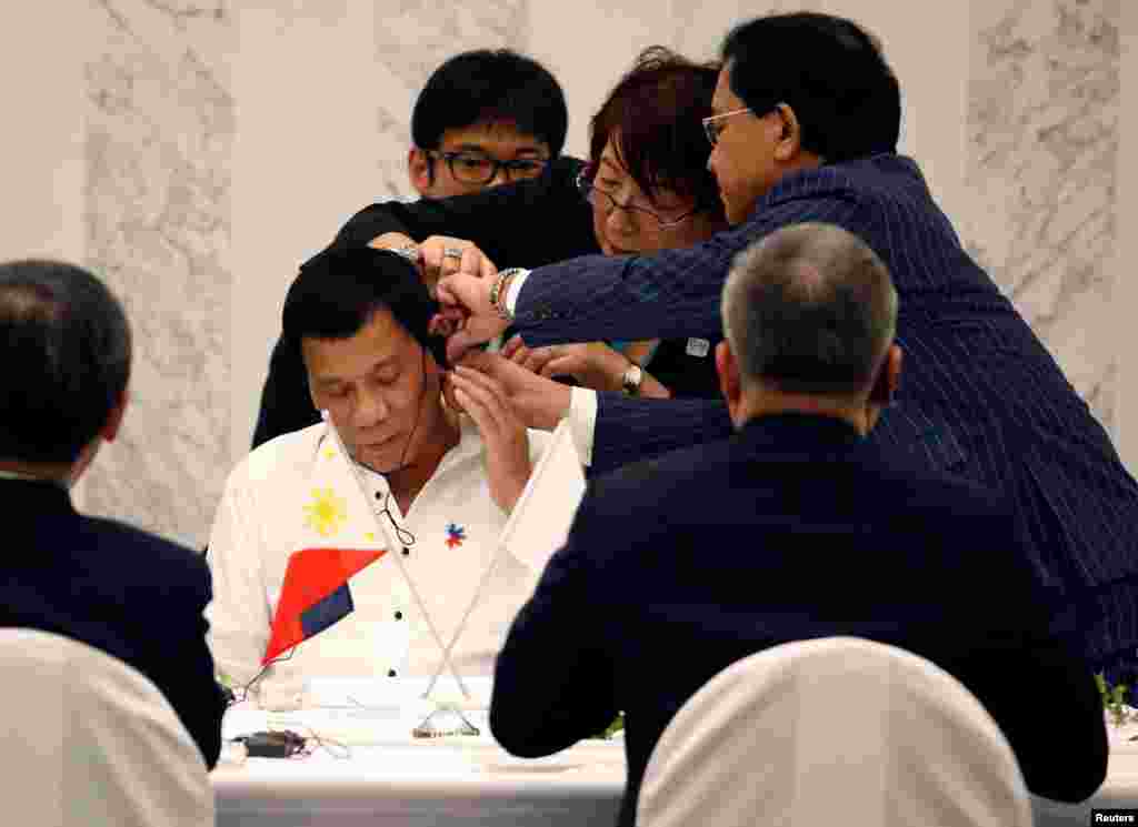 Presiden Filipina Rodrigo Duterte dibantu oleh penerjemah memasang piranti pendengaran (earphone) saat acara pertemuan dengan para tokoh bisnis Jepang di Tokyo.
