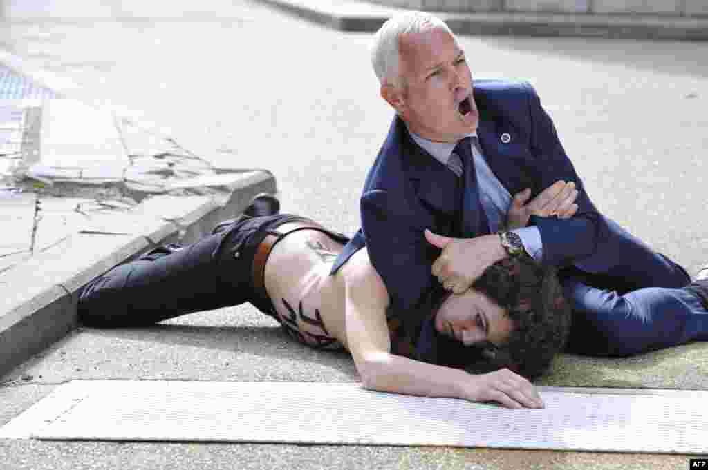 Seorang petugas keamanan membekuk seorang aktivis feminis 'Femen' saat mencoba menghentikan mobil Perdana Menteri Tunisia meninggalkan gedung komisi Uni Eropa di Brussels, Belgia.