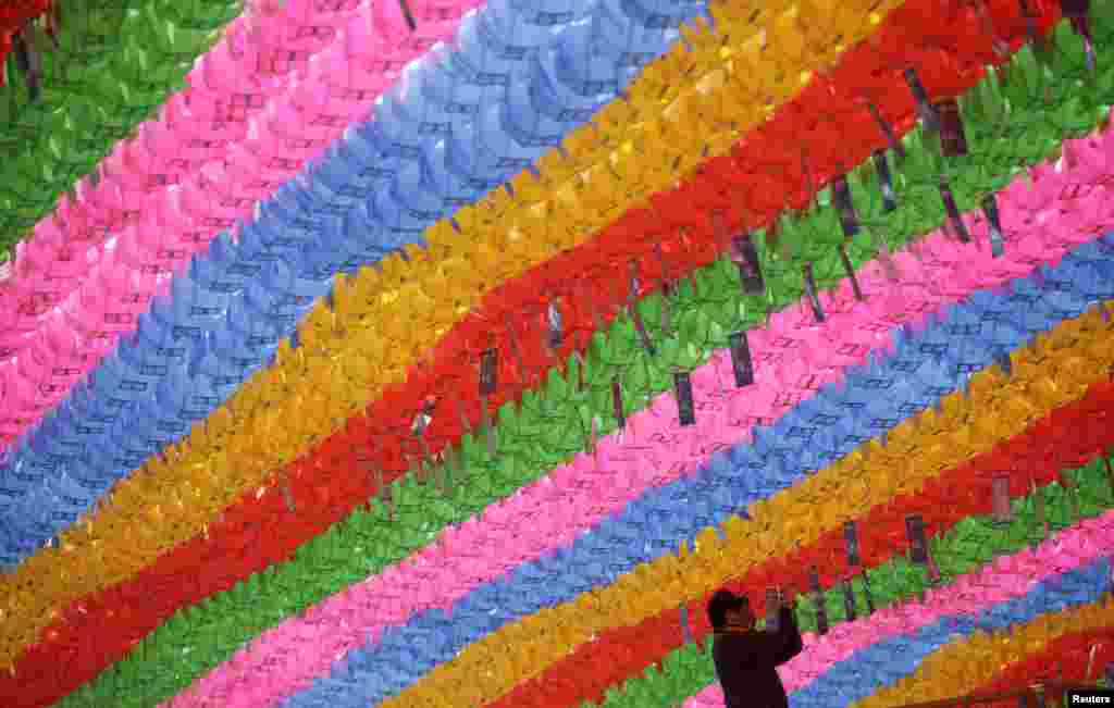 A worker attaches prayer petitions, with names written on cards, to lotus lanterns in preparation for the upcoming birthday of Buddha at Jogye temple in Seoul. Buddha's birthday falls on May 6 in South Korea.