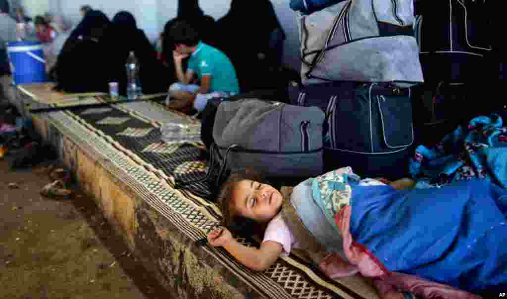 Một bé gái Syria nằm ngũ cạnh hành lý của gia đình tại cửa khẩu Bab Al-Salameh ở Azaz. Gia đình chạy lánh nạn này hy vọng sẽ được vào một trong các trại tị nạn ở Thổ Nhĩ Kỳ