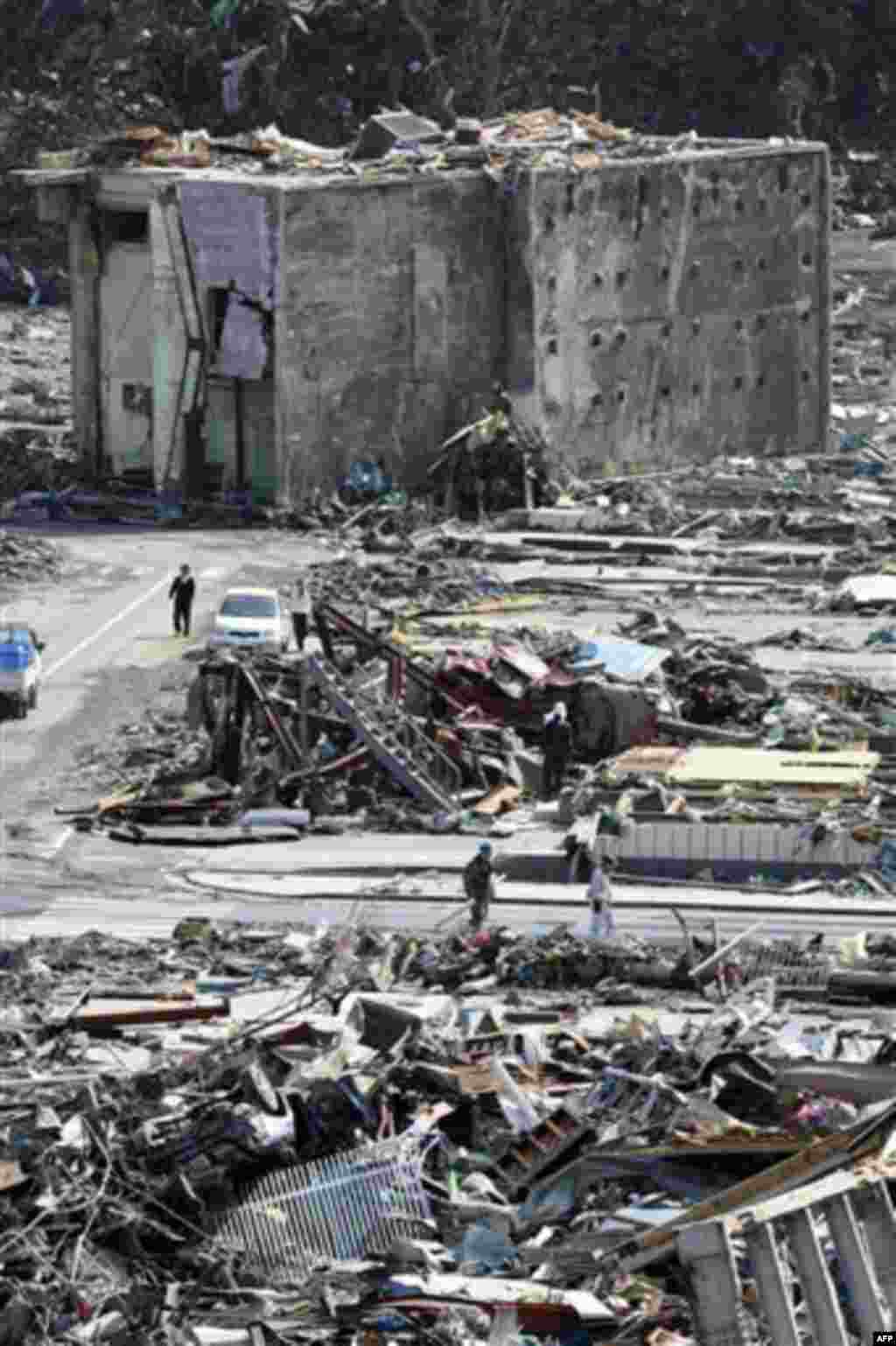 People walk through the rubble of destroyed buildings in Onagawa town, Miyagi Prefecture, northern Japan, Monday, March 14, 2011, three days after a powerful earthquake-triggered tsunami hit the country's east coast. (AP Photo/The Yomiuri Shimbun, Makoto