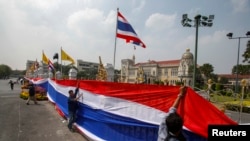 Para demonstran anti-pemerintah membungkus pintu gerbang dan pagar di sekeliling Wisma Pemerintah Thailand di Bangkok dengan spanduk raksasa berhias warna-warna bendera Thailand (13/12).