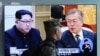 A South Korean marine passes by a TV screen showing file footage of South Korean President Moon Jae-in and North Korean leader Kim Jong Un, left, during a news program at the Seoul Railway Station in Seoul, South Korea, April 18, 2018.