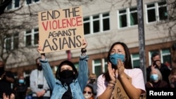 Dawn Cheung dan Victoria Do bertepuk tangan sambil mendengarkan pidato dalam unjuk rasa menentang kejahatan kebencian terhadap warga keturunan Asia di Hing Hay Park, Chinatown-International District of Seattle, Washington, Sabtu, 13 Maret 2021.
