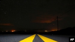Lights from Waimea, Hawaii, shine in the distance as wildfires burn in the area, Aug. 5, 2021. The region was scorched by the state's largest-ever wildfire.