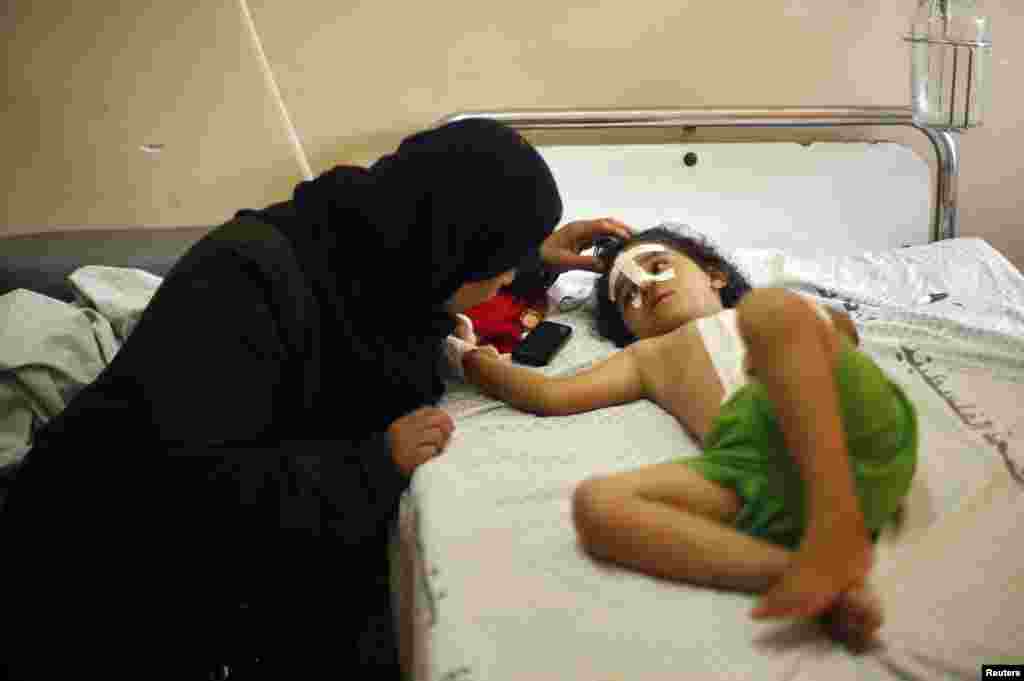 Four-year-old Palestinian girl Shayma Al-Masri, who hospital officials said was wounded in an Israeli air strike that killed her mother and two of her siblings, listens to her aunt as she lies on a hospital bed.
