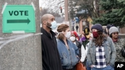 FILE - Voters masked against coronavirus line up at Riverside High School for Wisconsin's primary election, April 7, 2020, in Milwaukee.