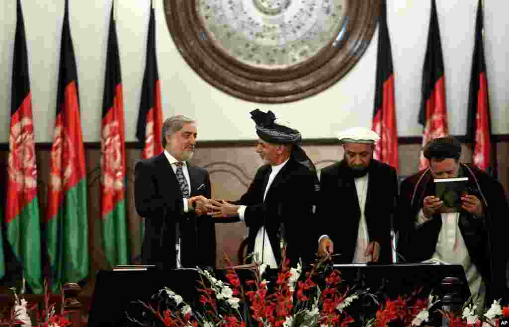 Afghan President Ashraf Ghani (second left) shakes hands with chief executive Abdullah Abdullah (left) during his inauguration ceremony at the presidential palace in Kabul, Afghanistan, Sept. 29, 2014.