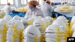 FILE - Workers produce face masks at a factory in Handan in China's northern Hebei province, Feb. 28, 2020.