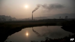 FILE - Smoke rises from a brick kiln on the outskirts of Gauhati, India, Jan. 26, 2015. Global health hinges on reducing greenhouse gas emissions, a climate change expert said Tuesday at the World Health Assembly in Geneva.
