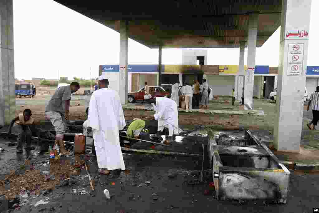 Men pick through debris after rioters torched a fuel station in Khartoum, Sudan, Sept. 26, 2013.