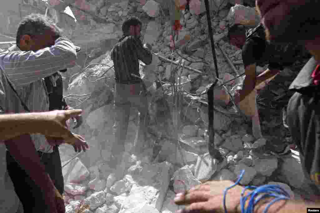 Civilians and members of the Free Syrian Army try to pull out a body from under the rubble of a building destroyed by a jet air strike in al-Kalaseh, Aleppo, Syria, September 19, 2012.