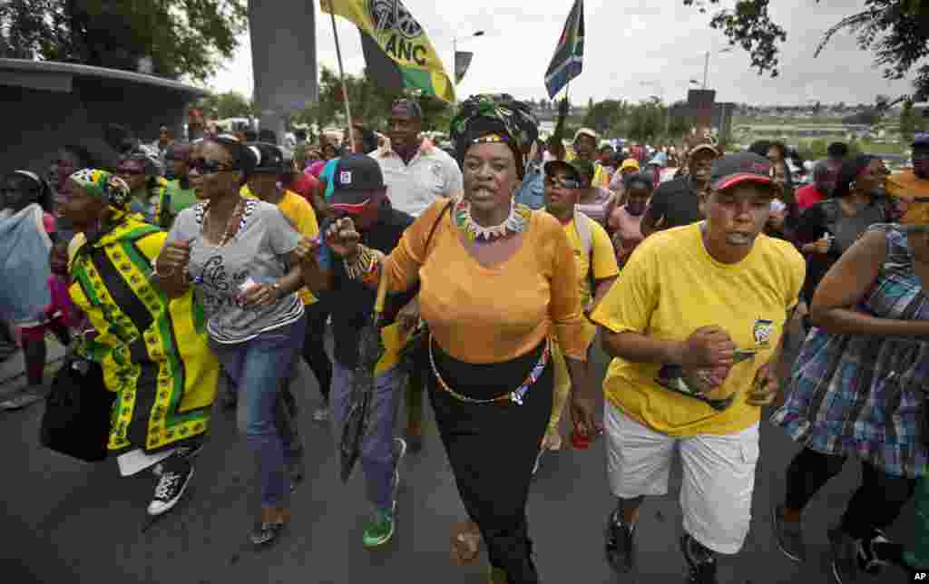 Township residents march to celebrate the life of Nelson Mandela in the street outside his old house in Soweto, Johannesburg, Dec. 6, 2013.