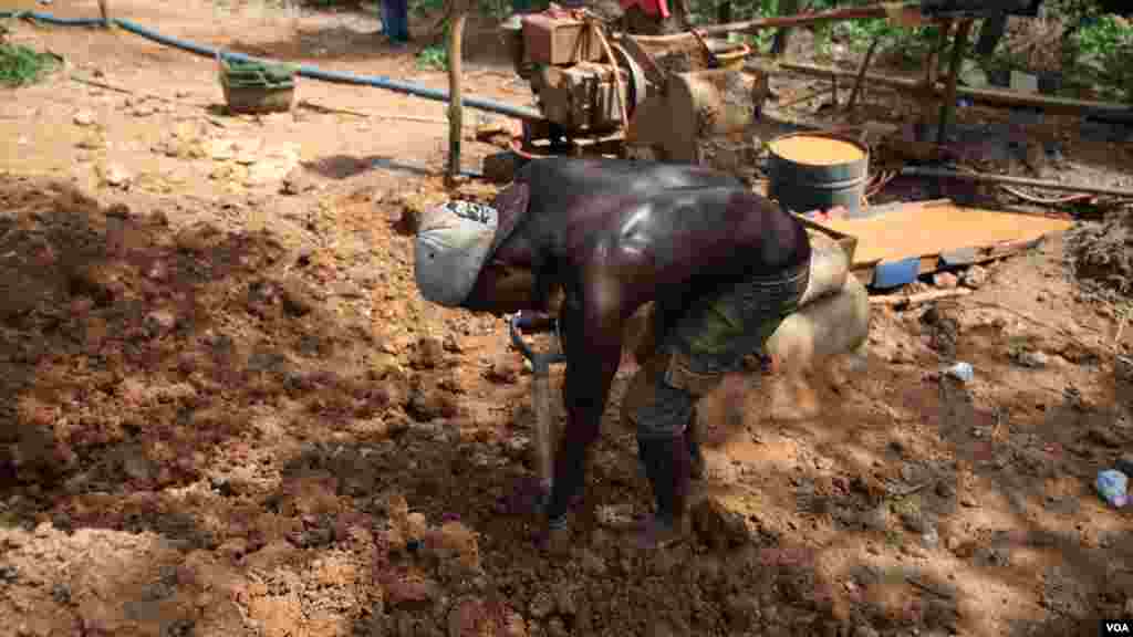 Un mineur utilise une pelle pour transporter la terre dans la petite mine d'Atunso Cocoase à Atunso, Ghana, le 16 octobre 2014. (Chris Stein / VOA).