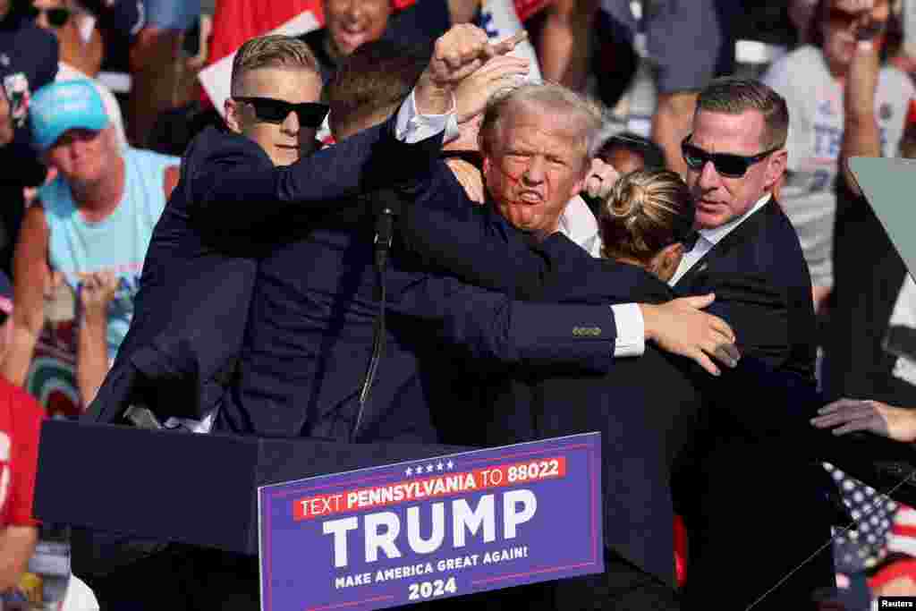 Republican presidential candidate and former U.S. President Donald Trump is assisted by U.S. Secret Service personnel after he was shot in the right ear during a campaign rally at the Butler Farm Show in Butler, Pennsylvania, July 13, 2024. 