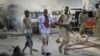 FILE - A Somali soldier helps a civilian who was wounded in a blast in the capital of Mogadishu, Oct. 14, 2017. 