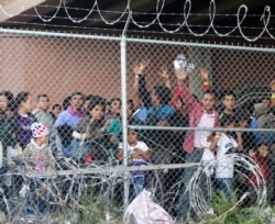 FILE - Central American migrants wait for food in a pen erected by U.S. Customs and Border Protection to process a surge of migrant families and unaccompanied minors in El Paso, Texas, March 27, 2019..